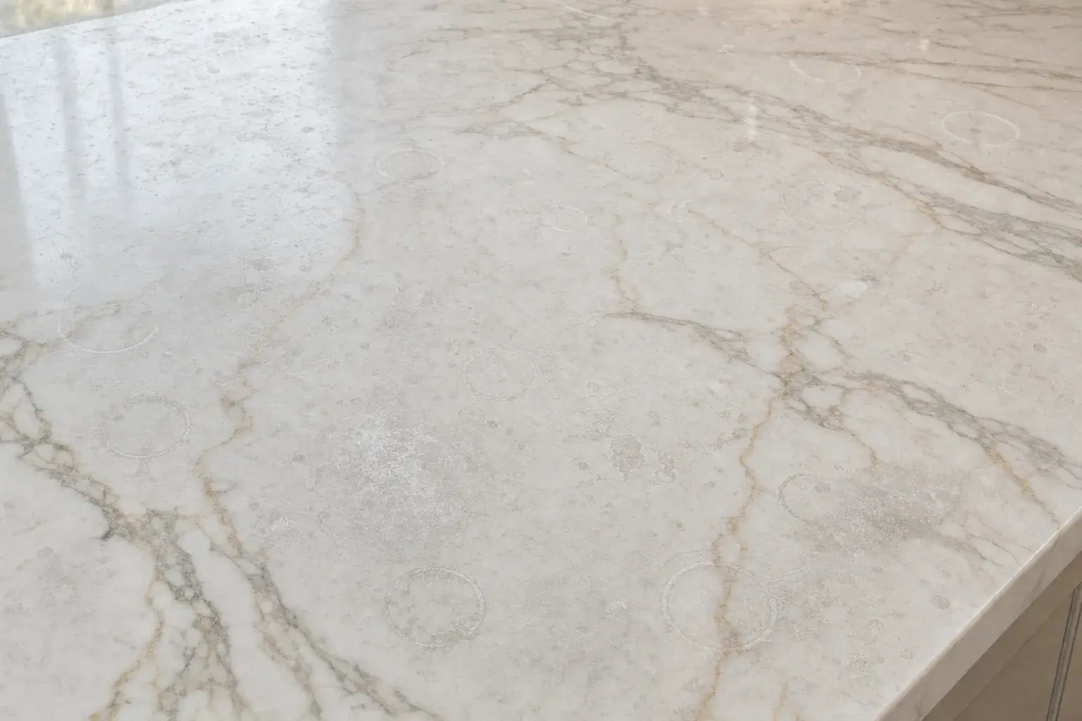 Marble benchtop dulled by years of etch marks and rings