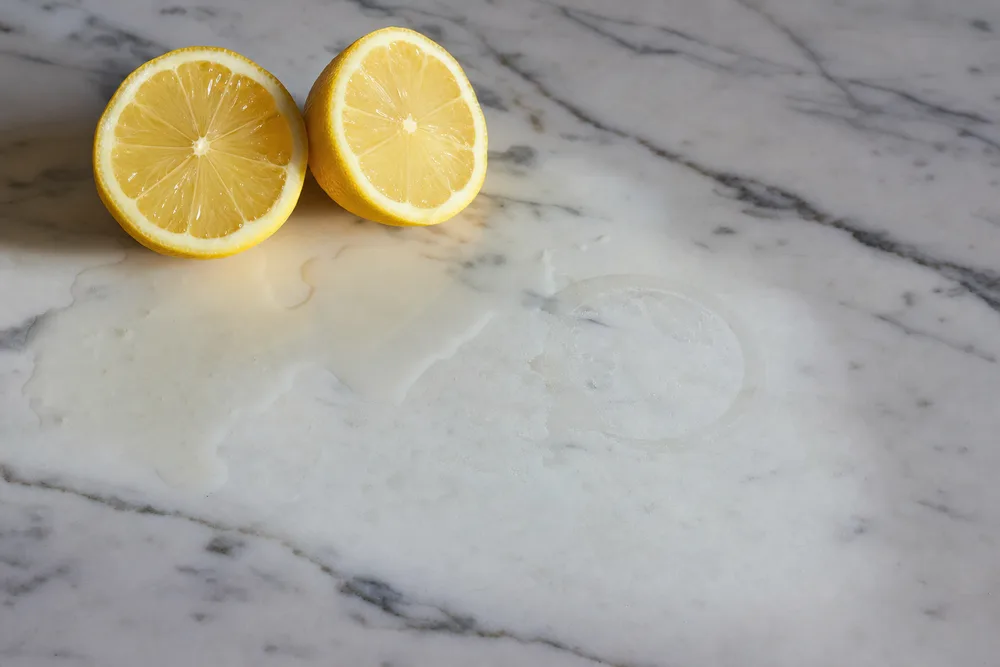 Dull etch marks on polished marble beside halved lemons