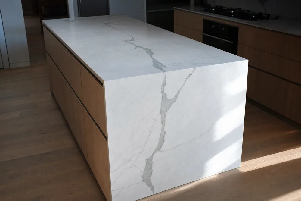 Pale marble island with a waterfall edge in daylight